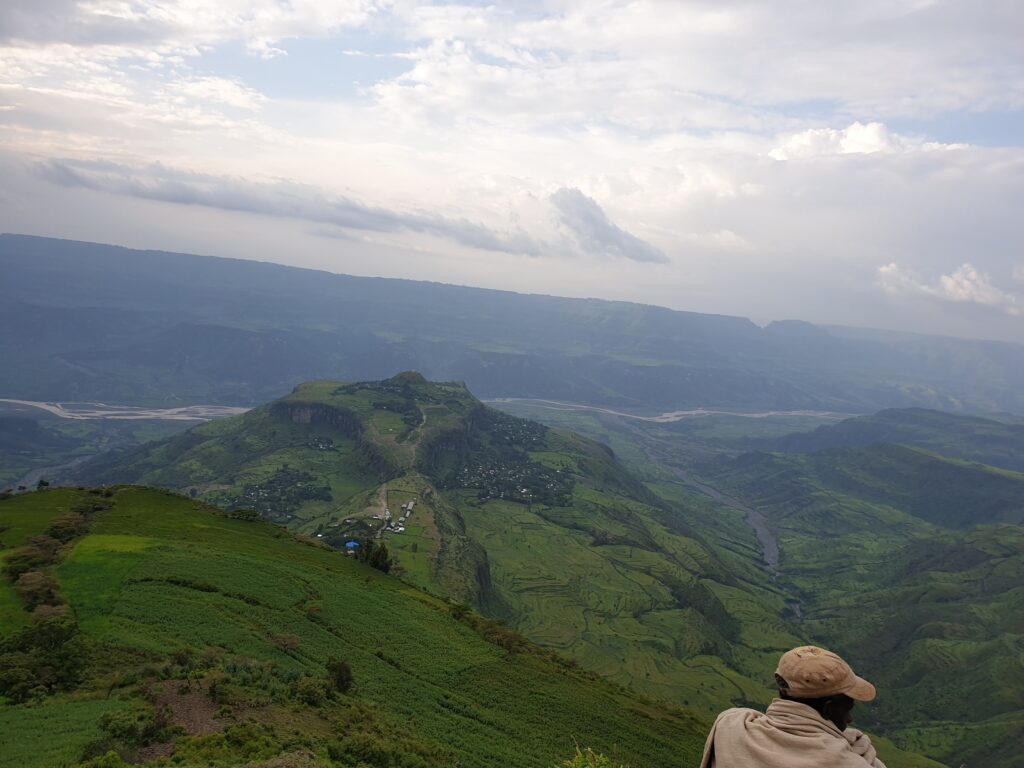 A person sitting on top of a hill looking at the sky.